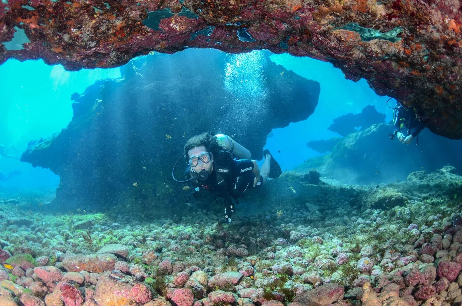 Plongeur sous-marin explorant un tombant rocheux dans une eau bleue claire
