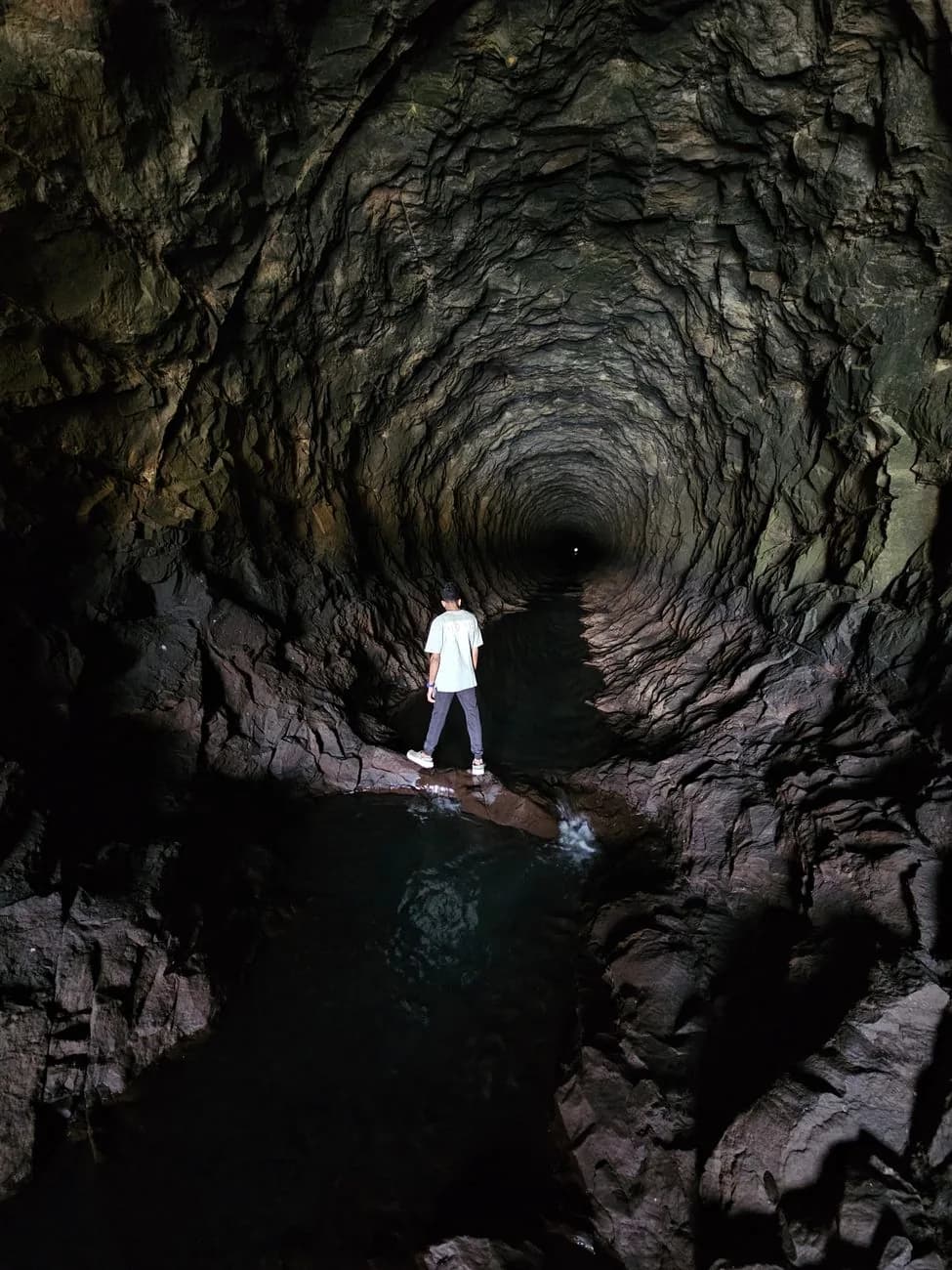 Randonneur dans un tunnel de levada creusé à la main dans la roche